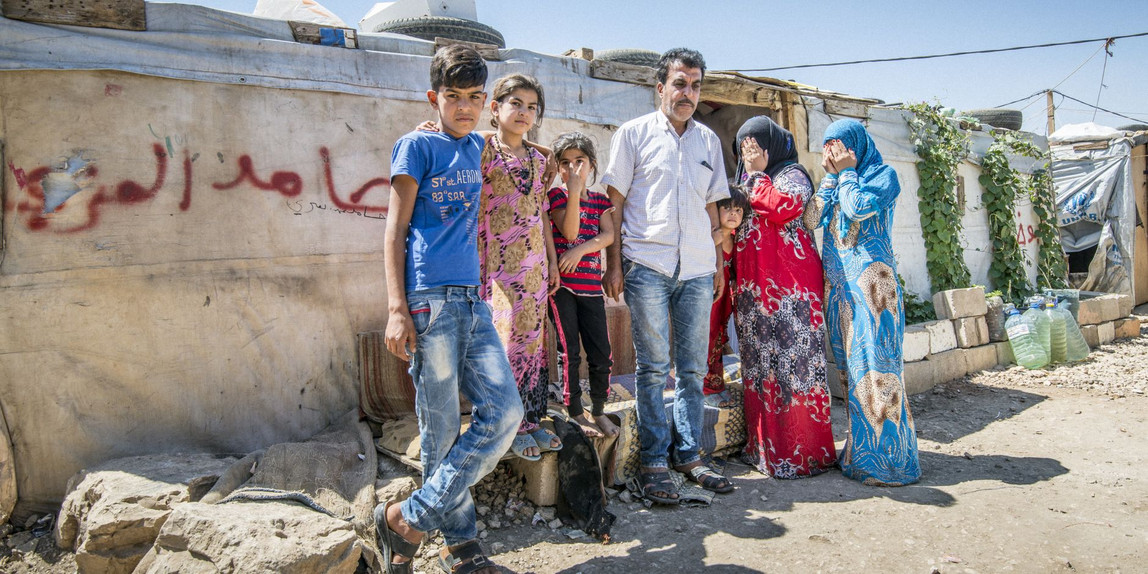 Eine Familie - in der Mitte der Vater, daneben drei Kinder, und rechts zwei Frauen, die sich beide die Hände vor das Gesicht halten